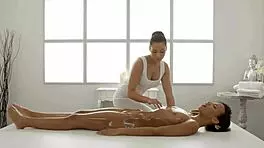 Two interracial lesbians kiss passionately before scissoring to intense orgasms during a massage