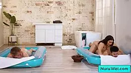 Sexy big beautiful busty masseuse handles two young 18+ boys in steamy nuru massage session.