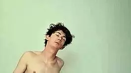 On a sunny day, this horny young teen masturbates with a big cock on the bed, getting cum covered.