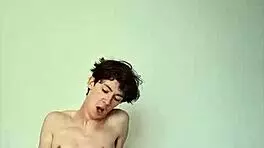 On a sunny day, this horny young teen masturbates with a big cock on the bed, getting cum covered.