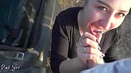 brunette black lynn with ponytail and brown eyes performs deepthroat blowjob and swallows cum in mouth from friend's big cock in car at sunset during outdoor public adventure.