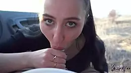 brunette black lynn with ponytail and brown eyes performs deepthroat blowjob and swallows cum in mouth from friend's big cock in car at sunset during outdoor public adventure.
