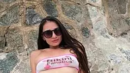 Beautiful brunette in bikini chills at beach with subtle flashing