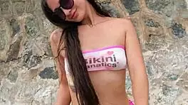 Beautiful brunette in bikini chills at beach with subtle flashing