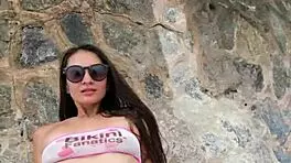 Beautiful brunette in bikini chills at beach with subtle flashing