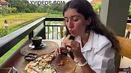 Enjoying a mouthful of pizza on the street in a public cafe with beautiful teen